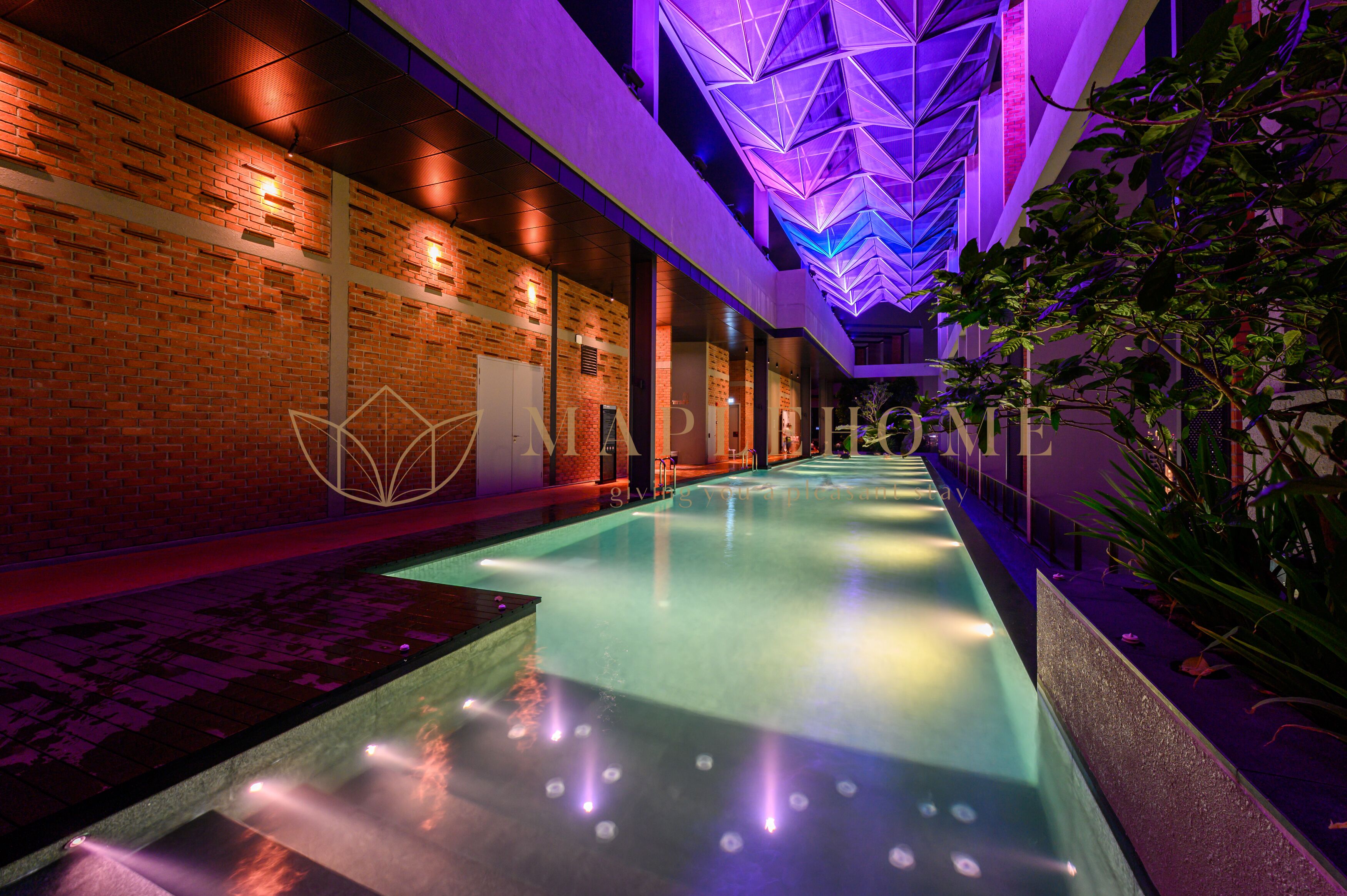 A spa area with a long, narrow pool, brick walls, and geometric ceiling lighting.
