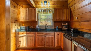A wooden cabin interior with a kitchen area, including cabinets, a sink, a microwave, and a toaster.