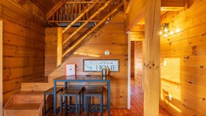 A wooden interior with a staircase, a table with chairs, and a 'HOME' sign.