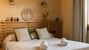 Un letto con struttura in legno, biancheria bianca, due cuscini e due asciugamani piegati.