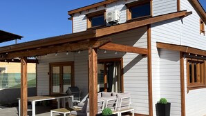 A two-story house with a covered patio area, outdoor furniture, and potted plants.