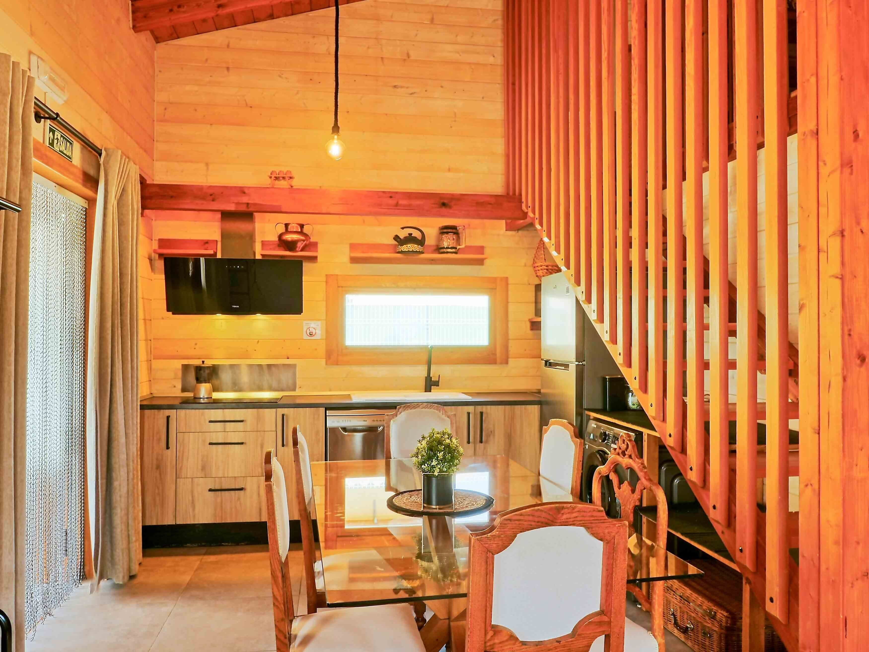 Un interior de madera con cocina, comedor y escalera.