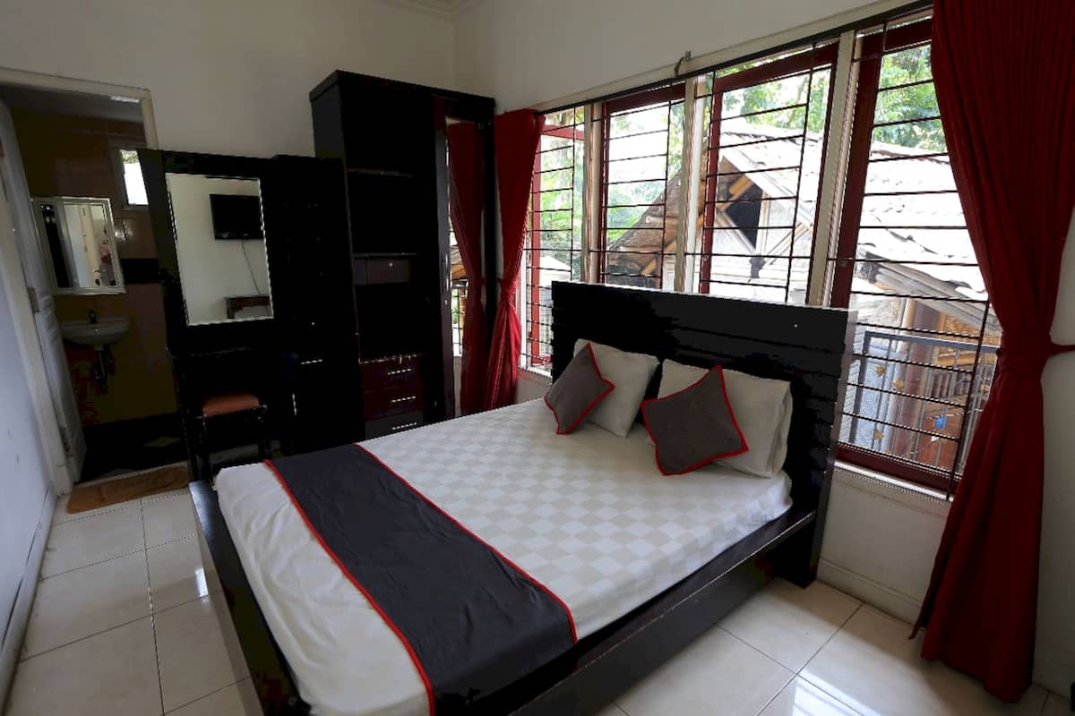 A bedroom with a bed, a wardrobe, a mirror, and a window with curtains.