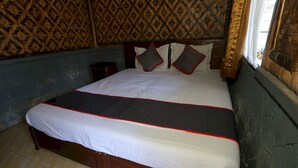 A bed with a white and red bedspread, a wooden headboard, and patterned wallpaper. - OYO 93159 Resort Cinta Kasih (Megamendung)