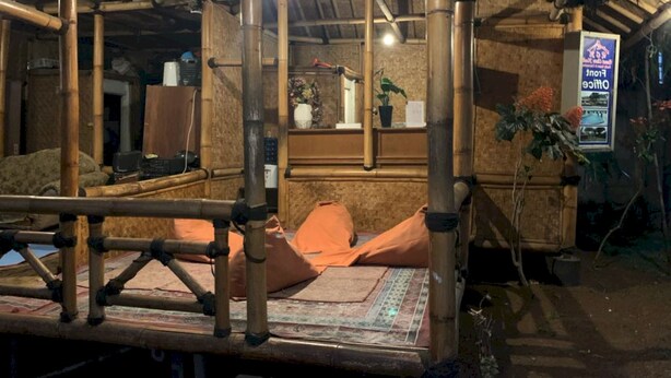 A bamboo structure with a bed and pillows, a small table, and a potted plant. - OYO 93159 Resort Cinta Kasih (Megamendung)