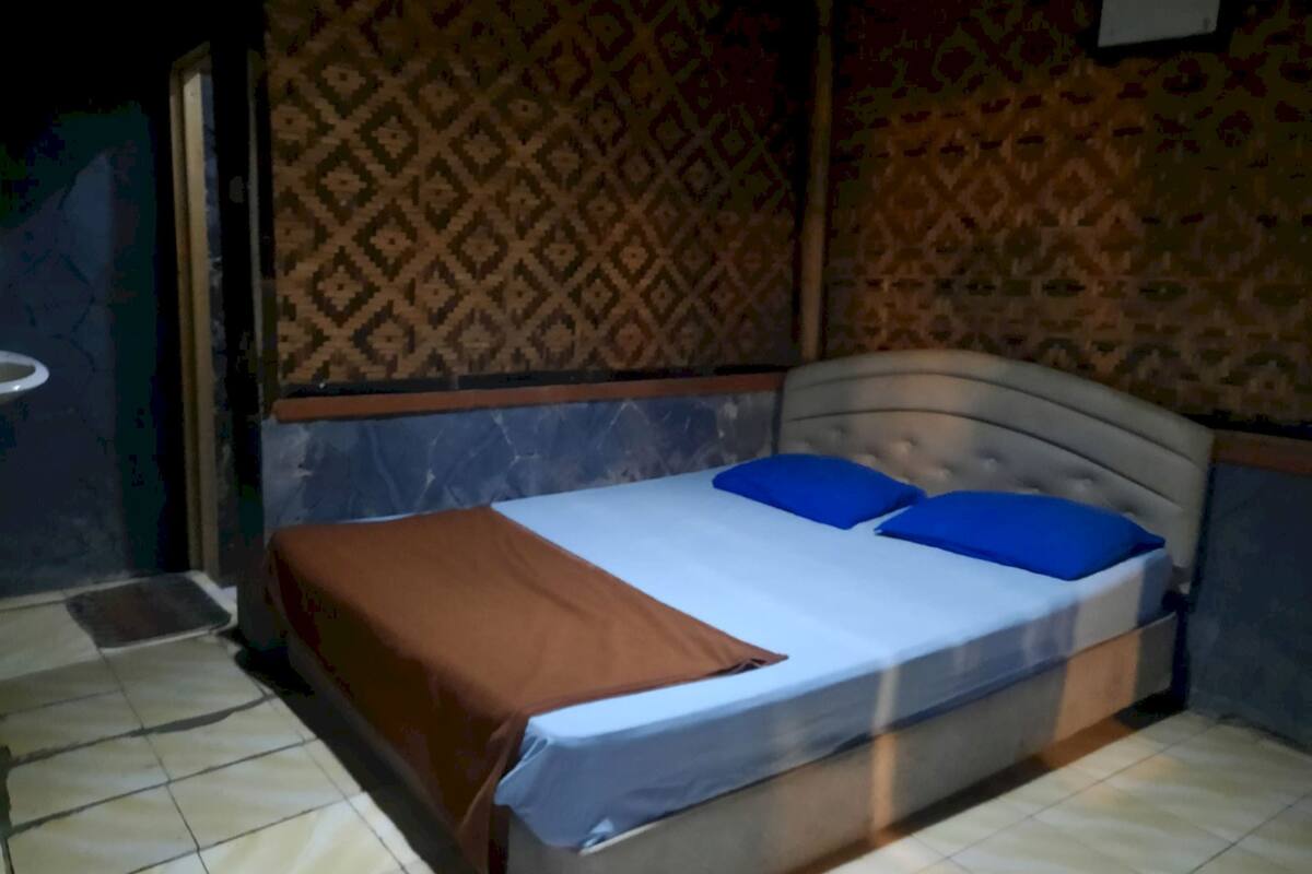 A bedroom with a bed, a bedside table, and patterned wallpaper.