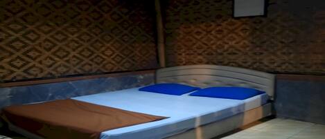 A bedroom with a bed, patterned wallpaper, and a tiled floor.