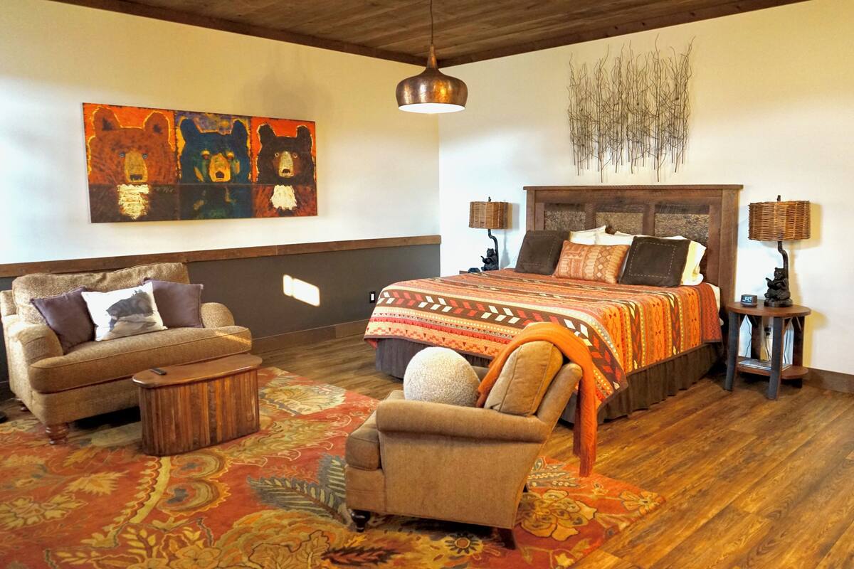 A room with a large bed, two side tables, a sofa, and a chair.