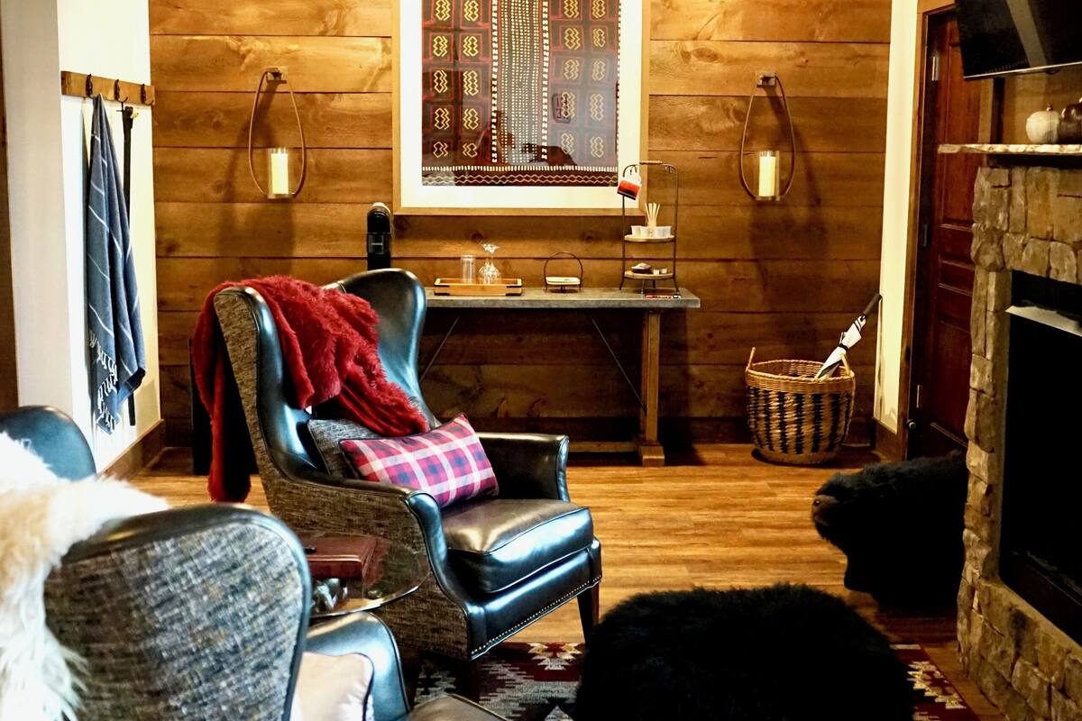 A cozy room with a fireplace, a wooden ceiling, a patterned wall hanging, and a comfortable seating area.