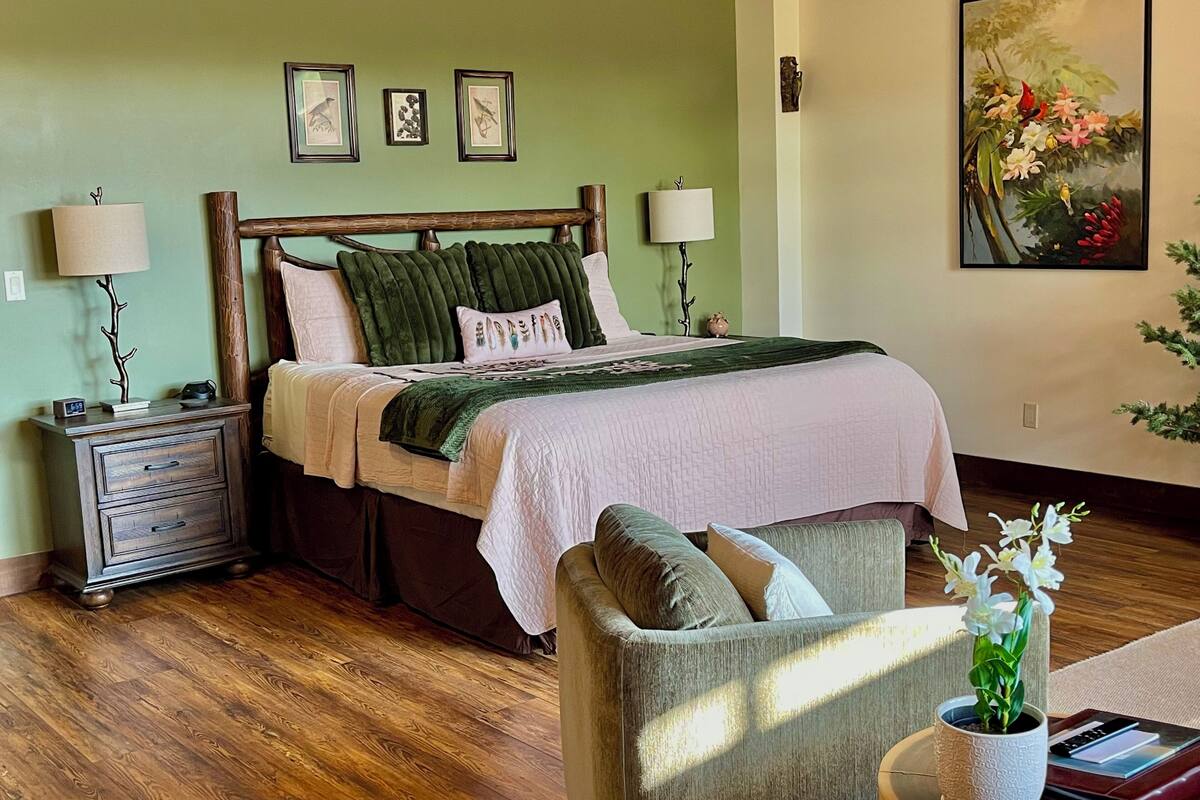 A bedroom with a bed, bedside tables, a chair, a nightstand, and a wall-mounted painting.