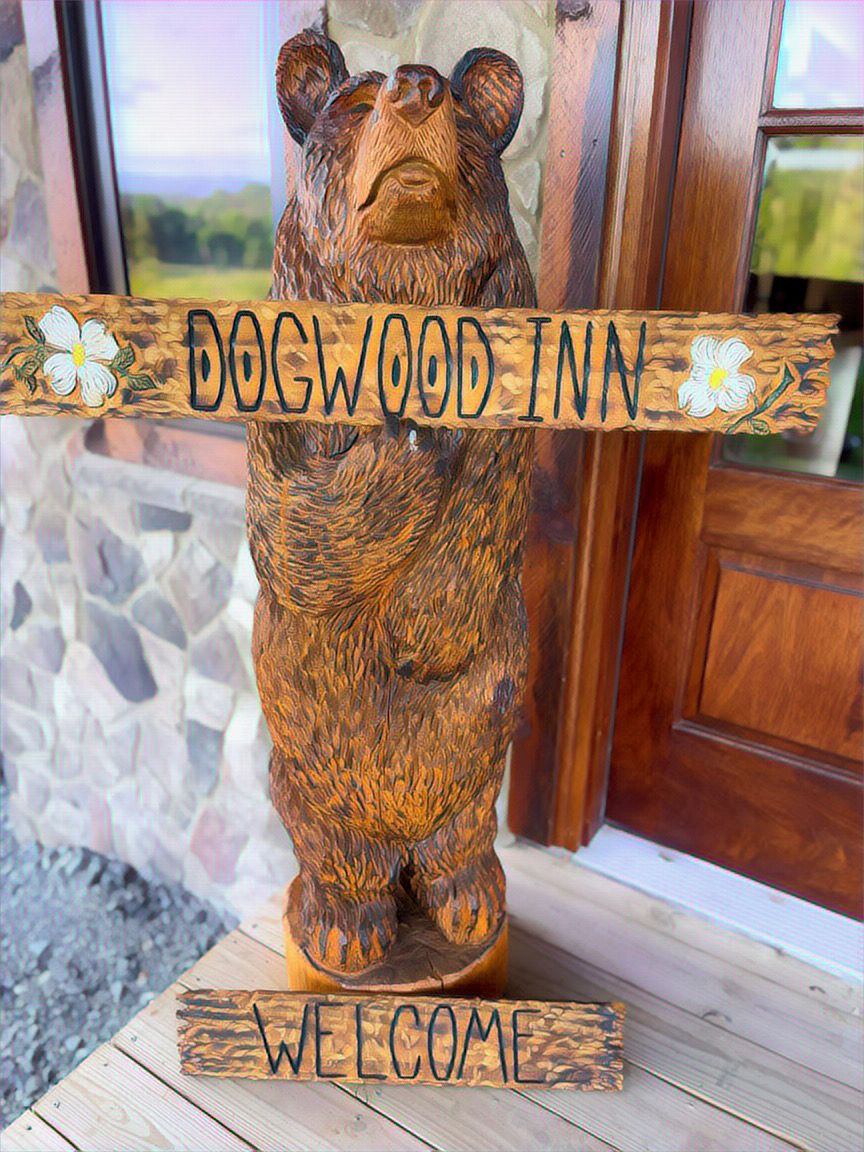 A wooden bear sculpture with "DOGWOOD INN" and "WELCOME" signs.
