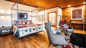 A cozy bedroom with a four-poster bed, a sitting area with chairs, and a wooden ceiling. - The Dogwood Inn (Blue Ridge)