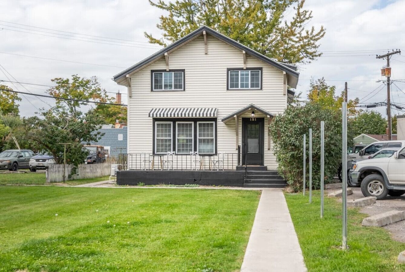 A two-story house with a front porch, a small front yard, and a sidewalk leading to the entrance.