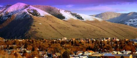 A town nestled in a valley with a backdrop of snow-capped mountains and a purple sky.