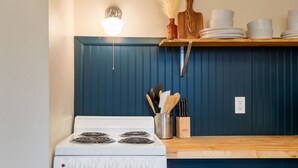 Une cuisine avec un four blanc, un plan de travail en bois et des meubles de rangement bleus.