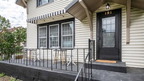 Une maison à deux étages avec une porte d’entrée noire et le numéro 121.