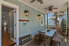 A covered porch with a table and chairs, a ceiling fan, and a view of the house.