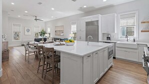 A spacious kitchen with a large island, white cabinetry, and a dining area with wooden chairs. - WaterColor PRIME Phase 1 Location! With NEW LSV & 4 Bikes! Walk to Seaside! (Santa Rosa Beach)