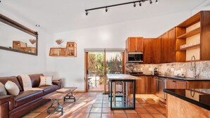 Eine moderne Küche mit Holzschränken, einer Marmorarbeitsplatte und einer Glastür, die auf eine Terrasse führt.