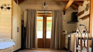 A spacious room with a bed, a dining table, and a kitchen area. - Luxury Rural Cuenca 2 (Nohales)
