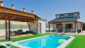 A backyard with a swimming pool, patio furniture, and a covered outdoor seating area. - Luxury Rural Cuenca 2 (Nohales)