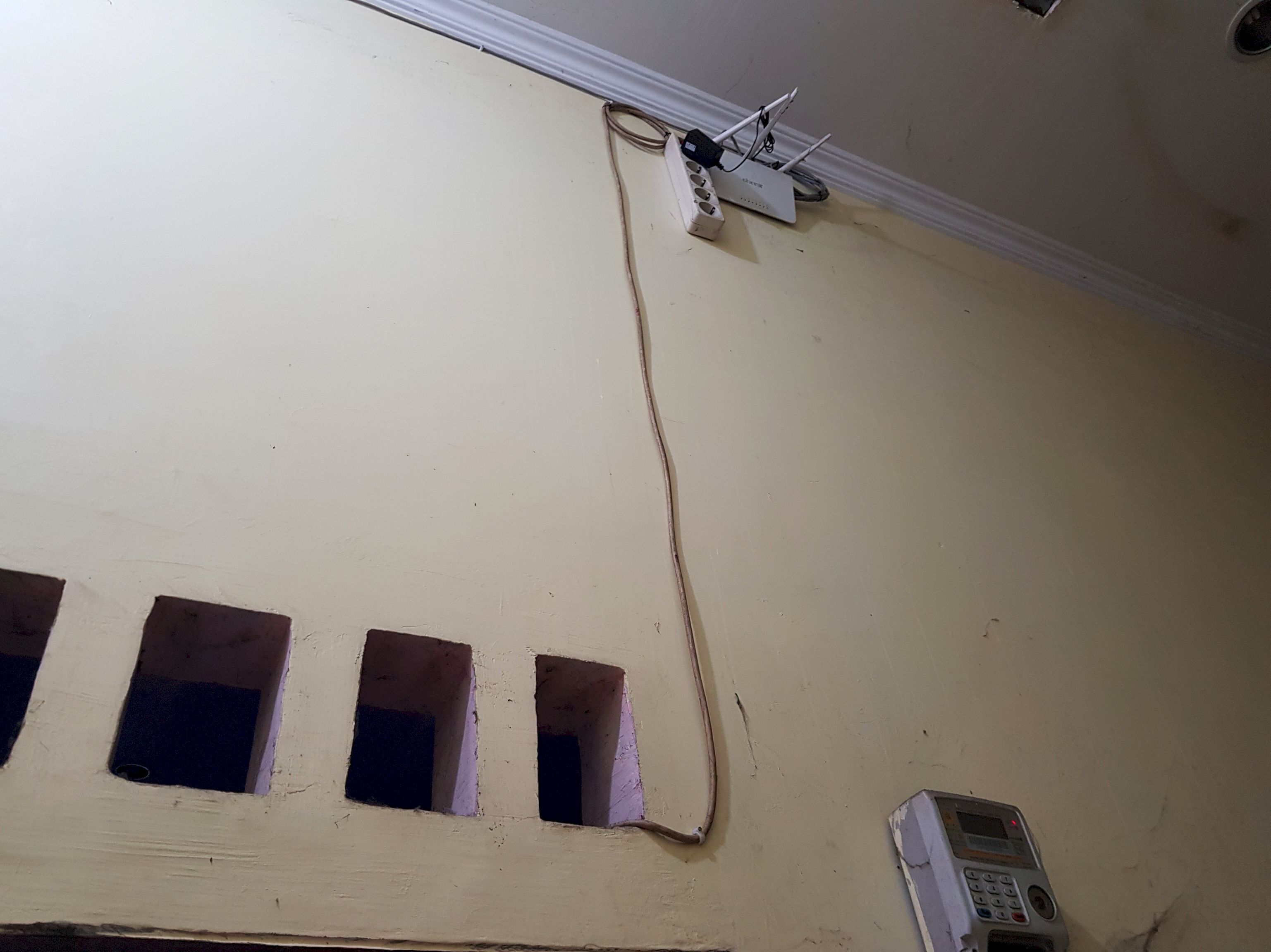 A room with a ceiling-mounted device, three small windows, and a wall-mounted telephone.
