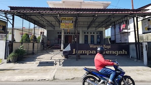 A building with a covered entrance and a sign advertising a business. - Hotel O Cempaka Syariah (Medan)