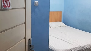 A small, single-bed room with a wooden headboard, a white door, and a 'No Smoking' sign on the wall. - Hotel O Cempaka Syariah (Medan)