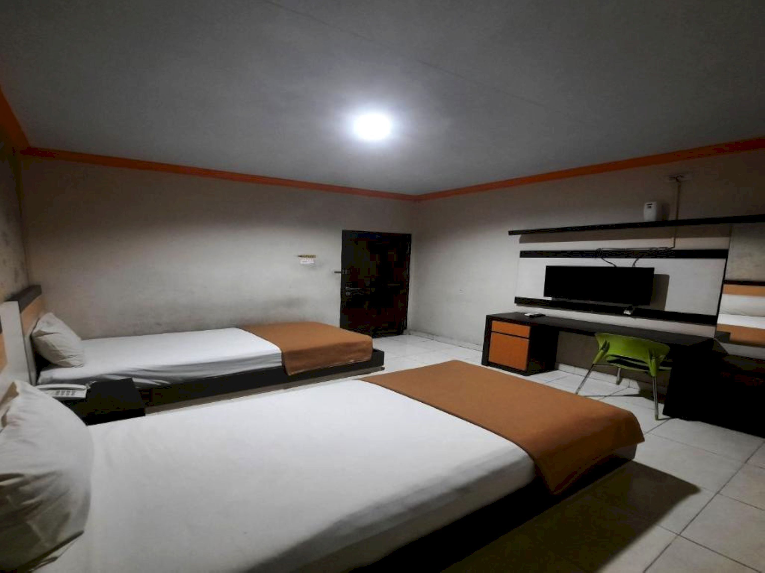 A hotel room with two single beds, a desk with a chair, a television, and a small cabinet.