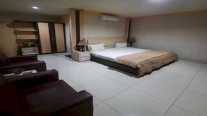A hotel room with a bed, bedside tables, a nightstand, a sofa, and a wardrobe. - Collection O 93163 Hotel Grand Kartika (Makassar)