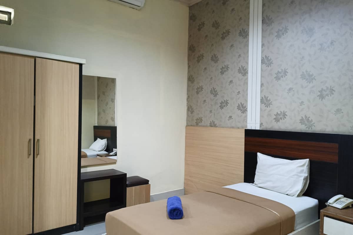 A hotel room with a bed, a wardrobe, a bedside table, and a mirror.