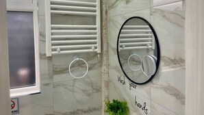 A bathroom with a white towel rack, a mirror with a black frame, and a sign that says "Wash your hands". - Nice And Cosy Large Studio Near Luton Airport! (Luton)