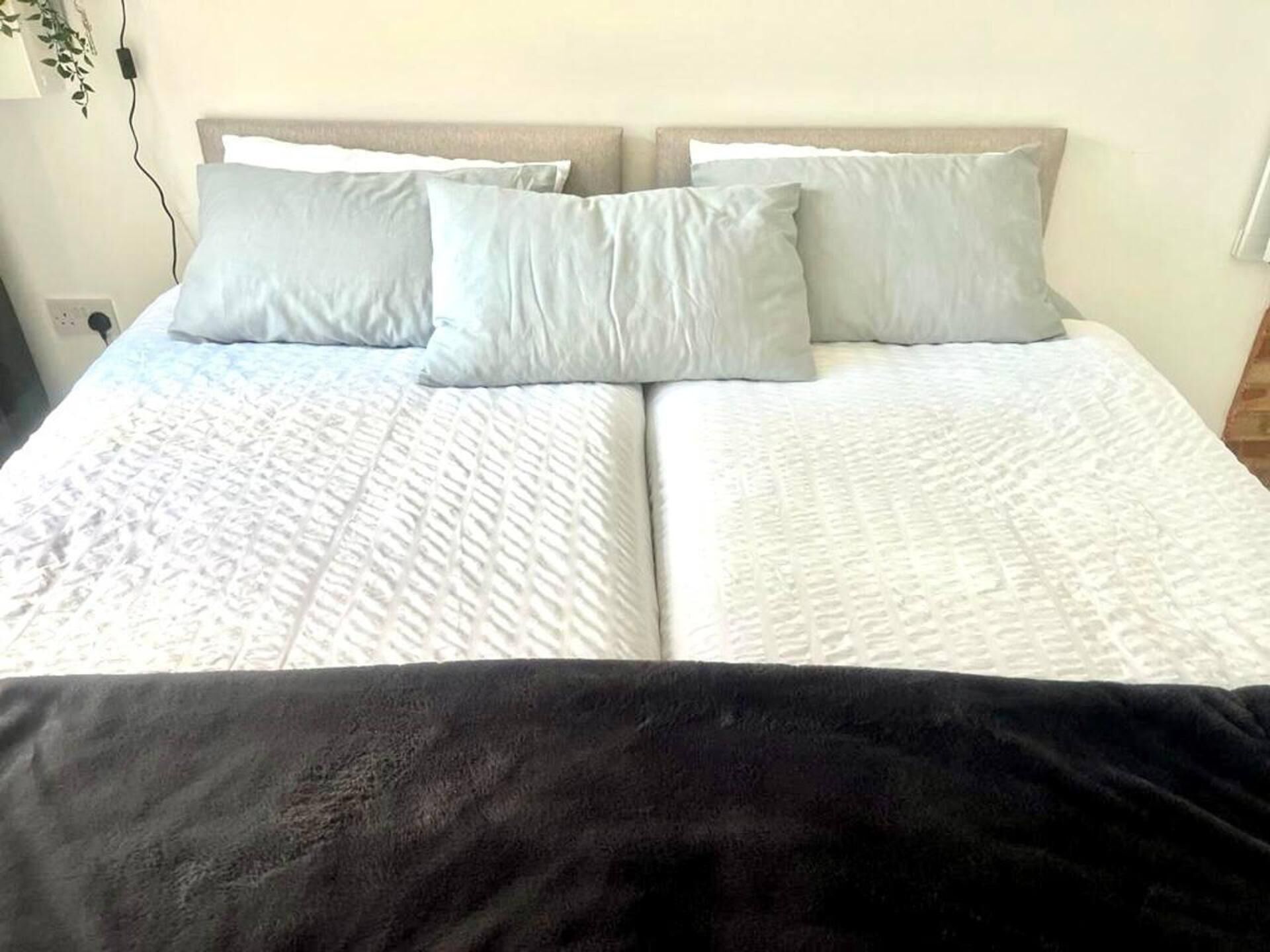 A double bed with a white quilted bedspread and two pillows.