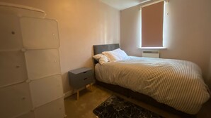 Una camera da letto con un letto, un comodino, una cassettiera e una finestra.