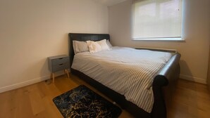 Una camera da letto con un letto, un comodino, una finestra con persiane e un tappeto con motivo marmorizzato.