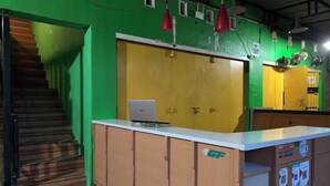A reception area with a wooden desk, a laptop, and a yellow door. - Hotel O Nur Homestay Syariah (Makassar)