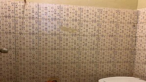 A bathroom with patterned tiles, a toilet, and a shower door. - Hotel O Nur Homestay Syariah (Makassar)