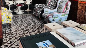 Un salon avec un sol à motifs, une lanterne rouge, un canapé agrémenté de coussins à fleurs, un tableau encadré et une table avec des chaises.