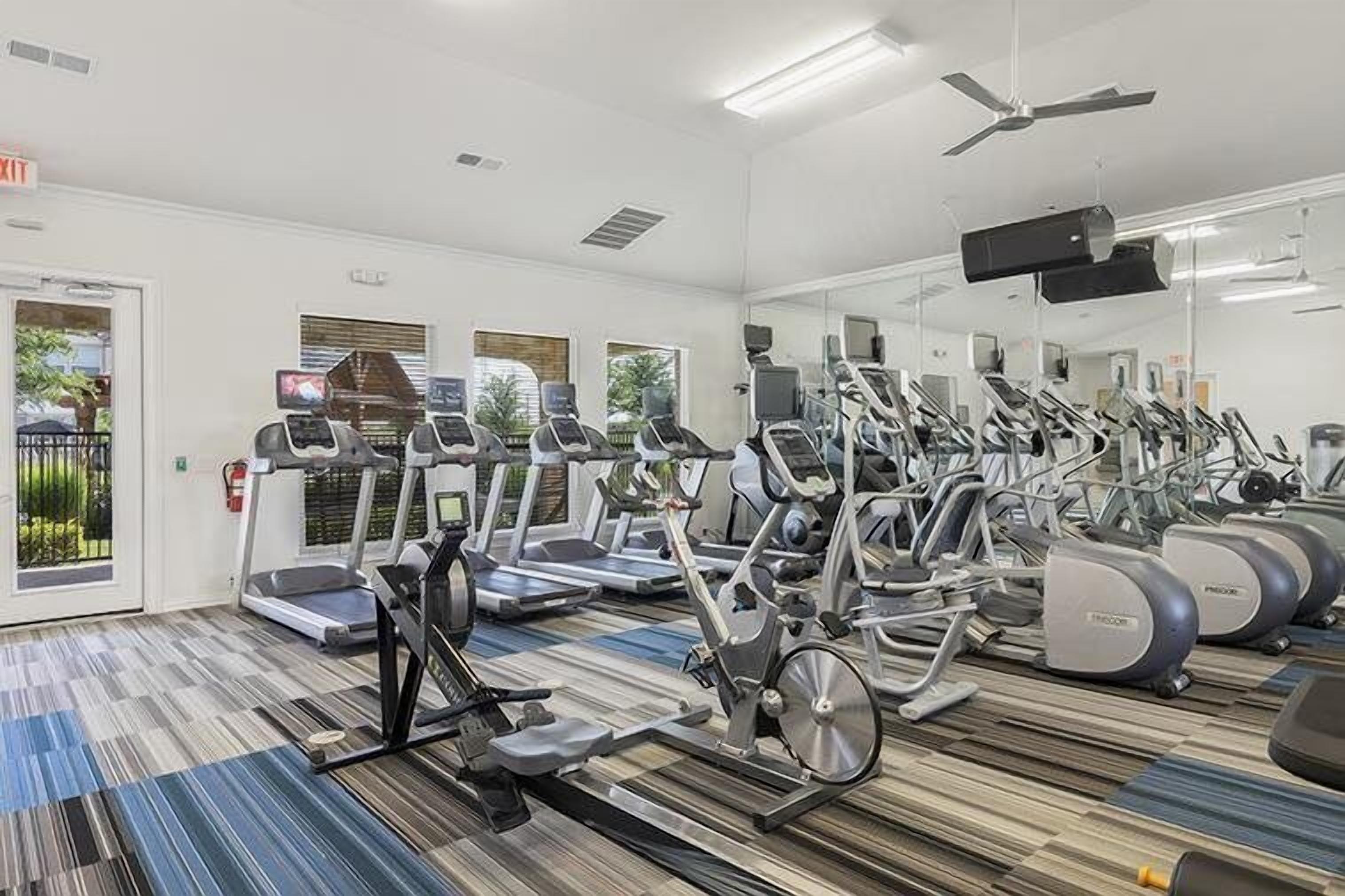 A gym with treadmills, elliptical machines, and stationary bikes.