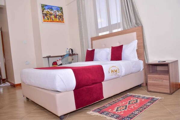 Habitación de hotel con cama, mesita de noche, un cuadro en la pared y ventana con cortinas.