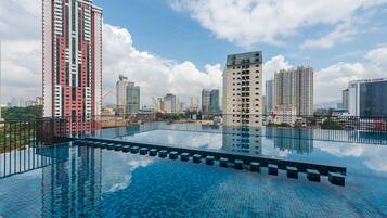 A rooftop infinity pool with a cityscape view, surrounded by high-rise buildings.