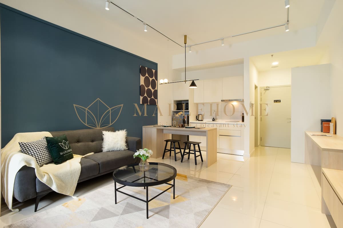 Una sala de estar moderna con sofá, mesa de centro y una cocina al fondo.