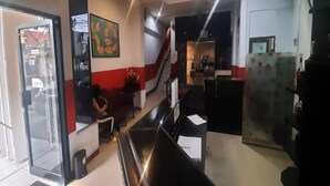 A hotel lobby with a reception desk, a staircase, and a glass door leading outside. - Hotel O Permata Ria Hotel (Manado)