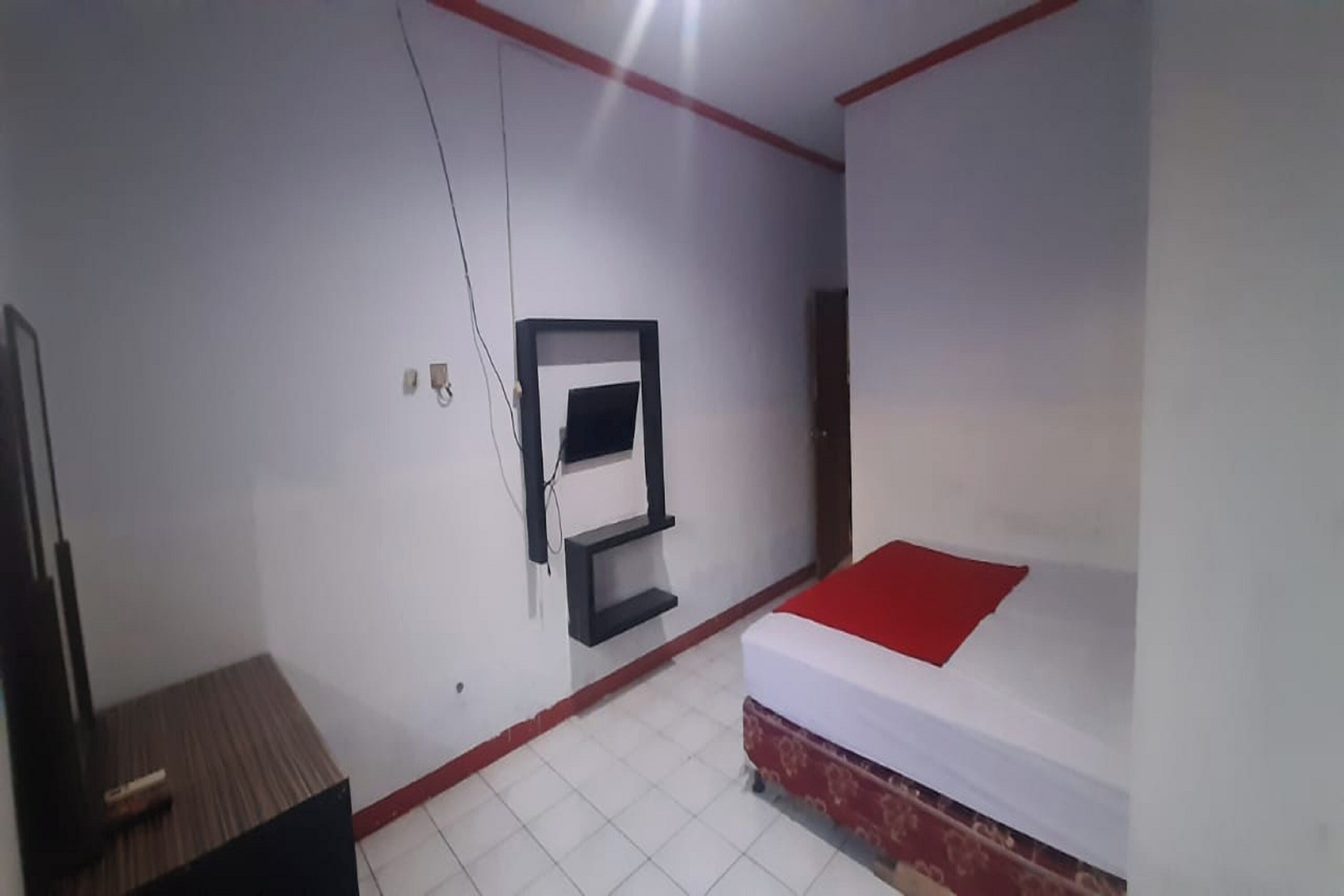 A small, simple room with a bed, a TV mounted on the wall, and a small table.
