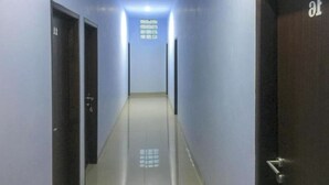 A corridor with doors on both sides, a tiled floor, and a ceiling light. - OYO 93169 Bnb Homestay  (Makassar)
