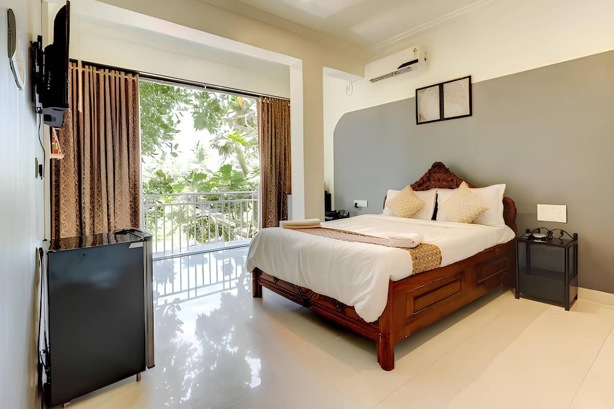 A hotel room with a large bed, a TV, a balcony, and an air conditioning unit.