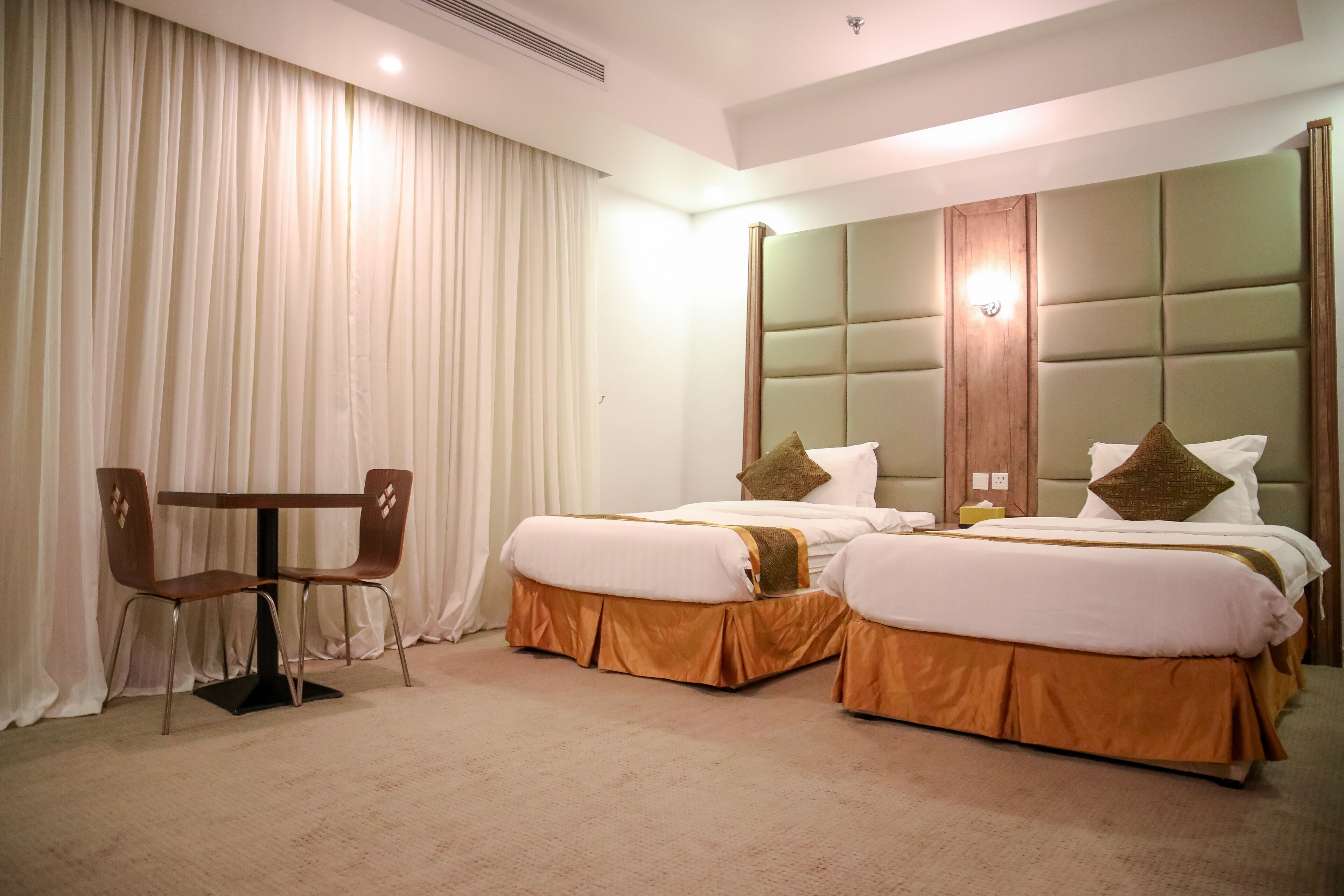 A hotel room with two beds, a table, and chairs.