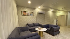 A modern living room with two grey sofas, a round coffee table, and a wall-mounted air conditioner. - Areen palace hotel (Jeddah)