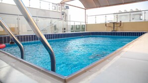 A swimming pool with a metal ladder and a covered area. - Areen palace hotel (Jeddah)
