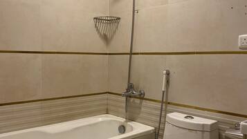 Un baño con bañera, cabezal de ducha y retrete.